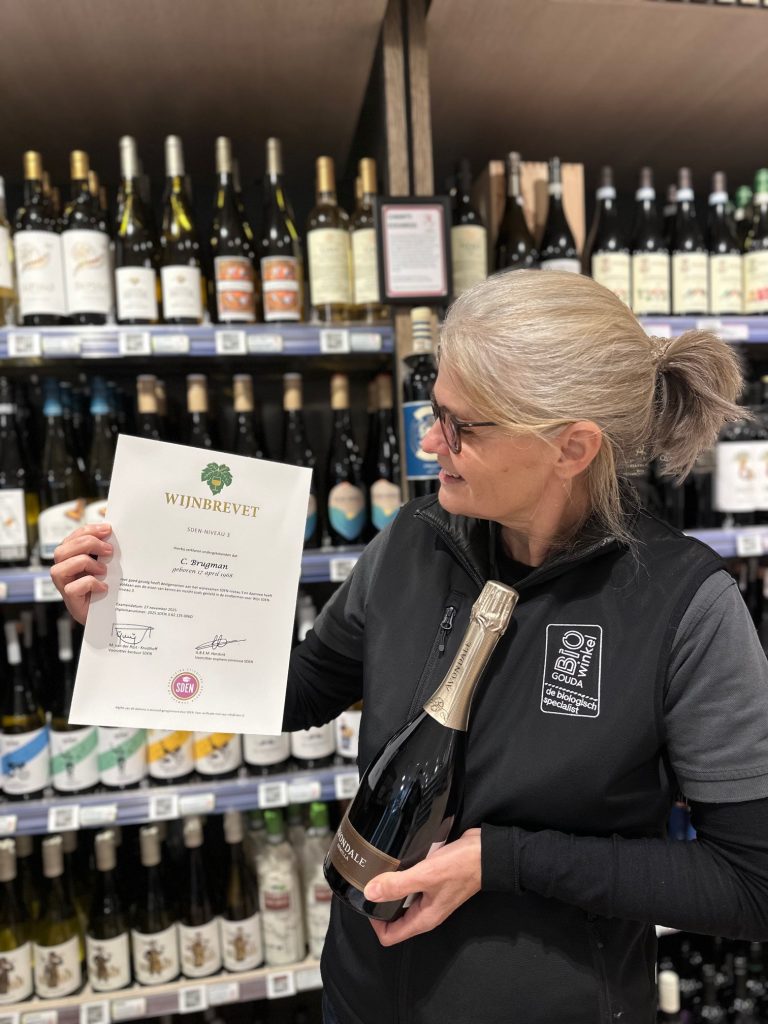 Céline met haar wijnbrevet SDEN3 poserend voor het wijnschap in de Biowinkel